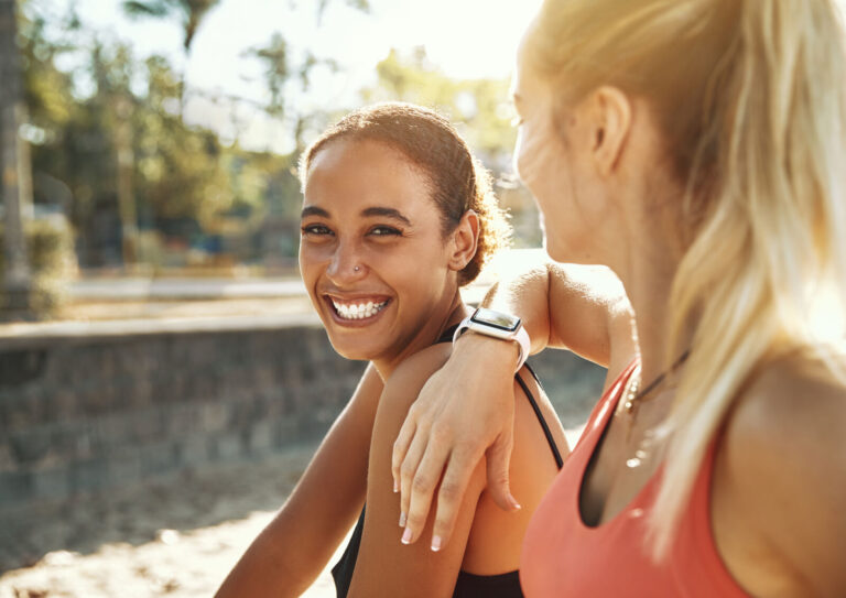Twee lachende jonge vrouwen buiten na het sporten