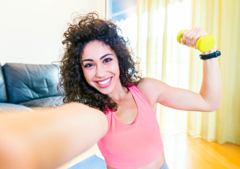 Lachende jonge vrouw sport thuis met een halter