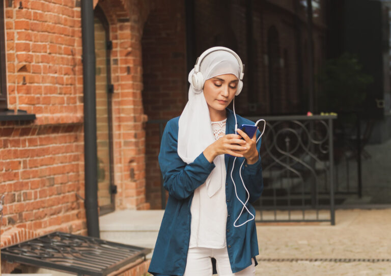 Jonge vrouw met koptelefoon kijkt op haar telefoon